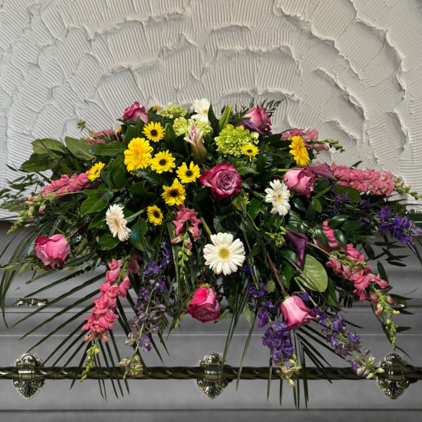 Casket spray with pink roses, yellow daisies, and purple flowers