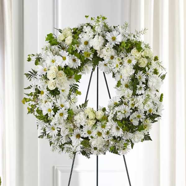 White floral wreath on a black stand