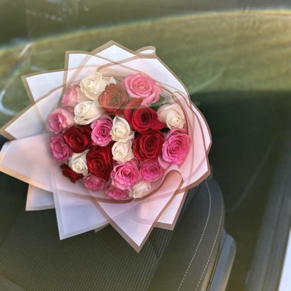 Bouquet of pink, red, and white roses wrapped in pale paper