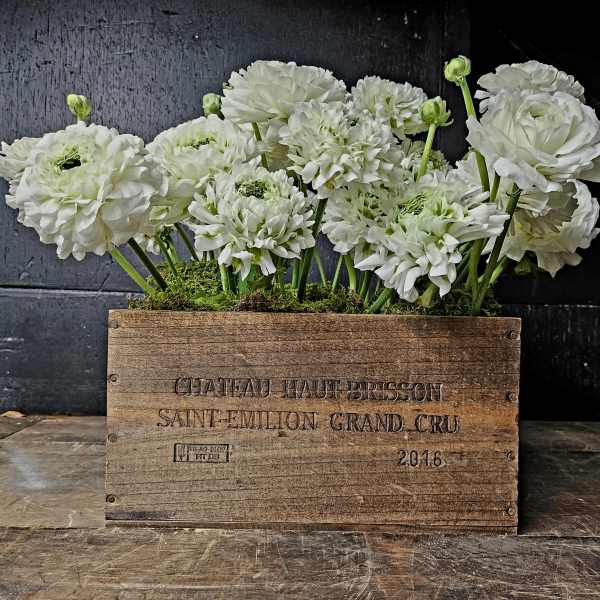 White ranunculus flowers arranged in a wooden crate