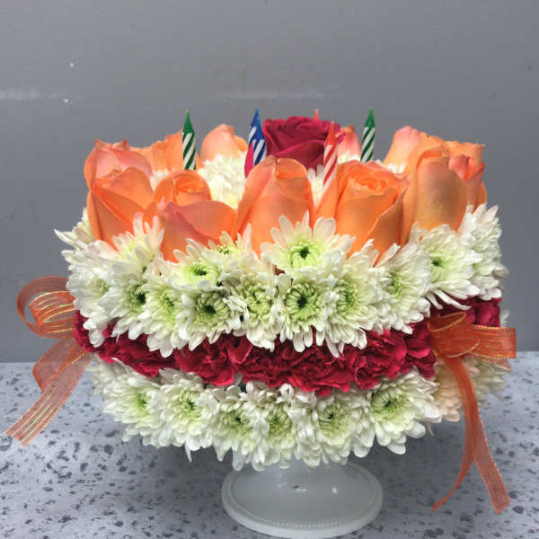 Orange roses and white daisies arranged on a cake stand with candles