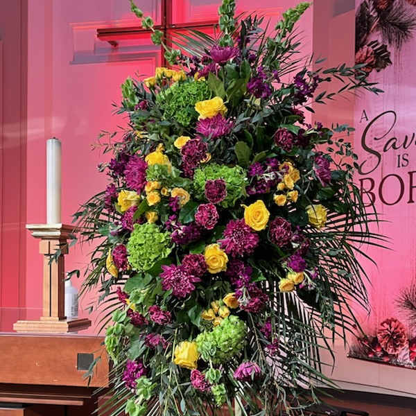 Tall standing floral spray with yellow and purple blooms on an easel