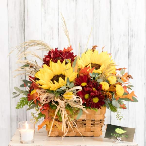 Basket arrangement of sunflowers and red mums with autumn accents