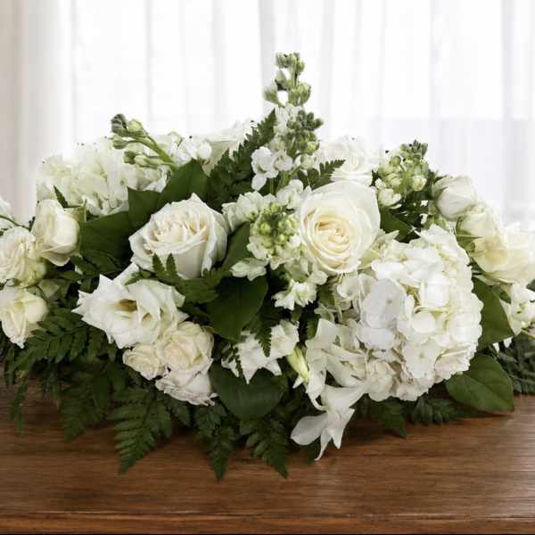 Low white floral arrangement with roses and hydrangeas on a table
