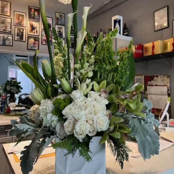 Tall white floral arrangement in a white box with calla lilies and roses
