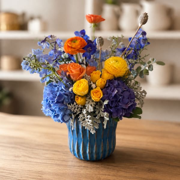 Colorful bouquet of blue, purple, yellow, and orange flowers in a blue vase