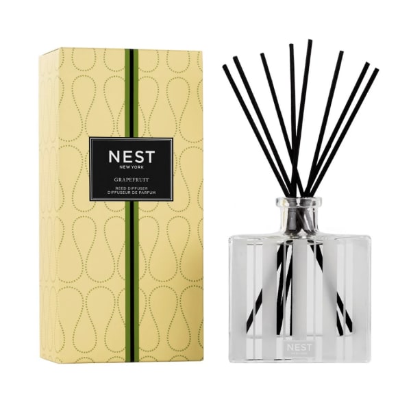 Reed diffuser with black sticks beside a yellow Nest New York box