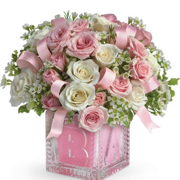 Pink and white rose arrangement in a glass block vase with ribbons