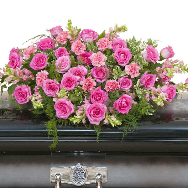 Pink rose and carnation casket spray arranged on a dark metal casket