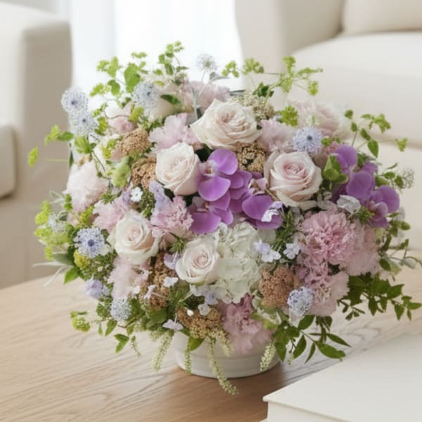 Pastel bouquet of roses, orchids, and hydrangeas in a white vase