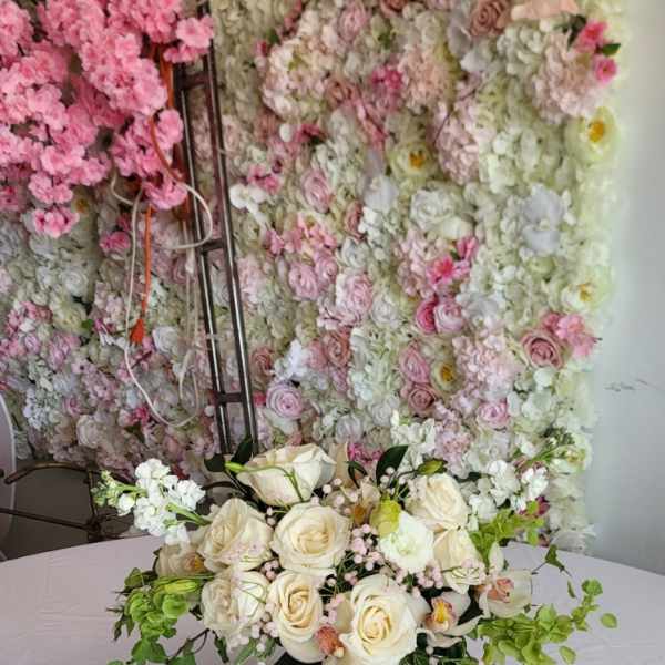 Cream rose arrangement in a patterned vase with trailing greenery