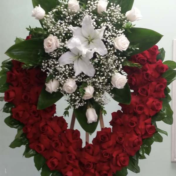 Heart-shaped red rose wreath with white lilies and roses on an easel