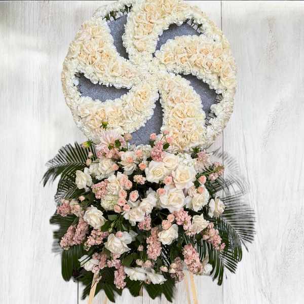 Large floral wreath with cream roses and pink flowers on a stand