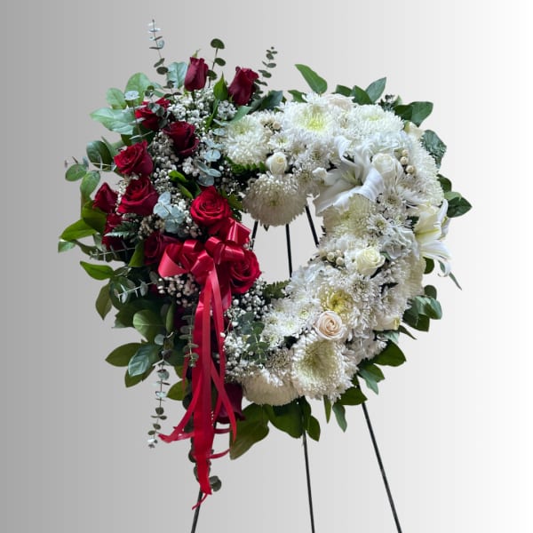 Heart-shaped floral wreath with red and white roses on an easel