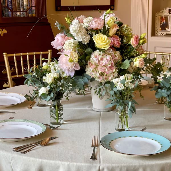 Pastel floral centerpiece with roses and hydrangeas on a dining table