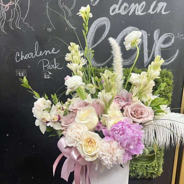 Pink and white floral arrangement in a white hatbox with ribbon