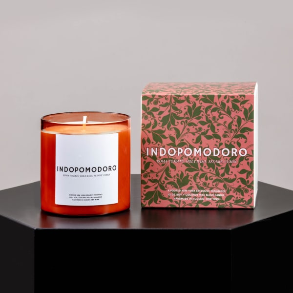 Orange candle in a glass jar beside its patterned box