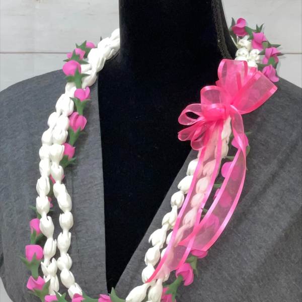 Braided white and pink floral lei with a bright pink ribbon bow displayed on a dark mannequin.