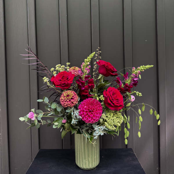 Tall vase arrangement with red roses and pink blooms