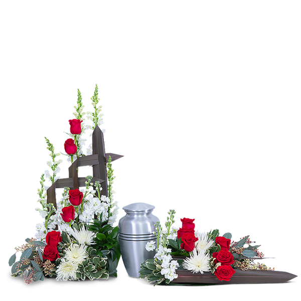 Red roses and white flowers arranged around a silver urn and wooden cross
