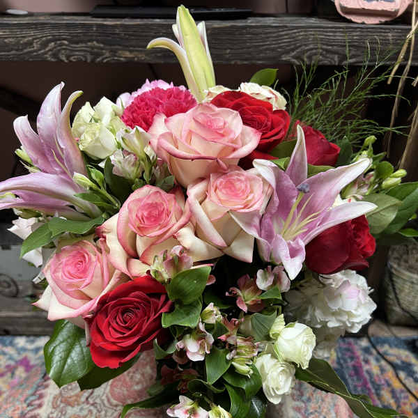 Bouquet of pink and red roses with lilies and white filler flowers