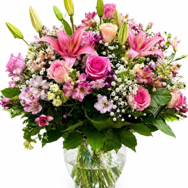 Pink lilies and roses arranged in a clear glass vase
