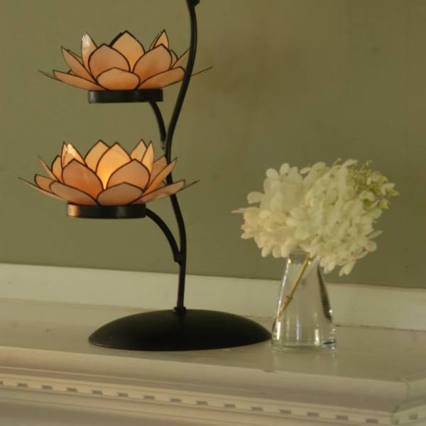 Three orange lotus-shaped candle holders on a black metal stand