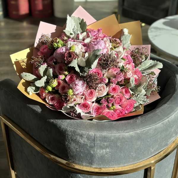 Bouquet of pink roses and pale blooms wrapped in pastel paper