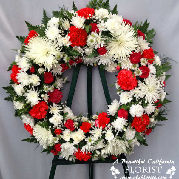 Red and white floral funeral wreath on a stand