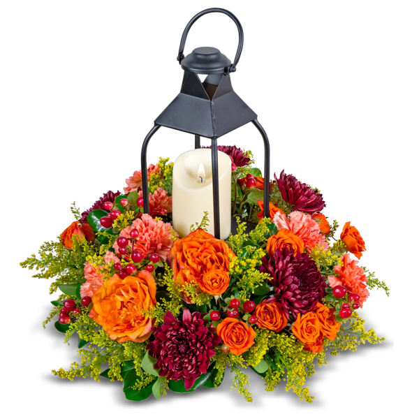 Lantern with a candle surrounded by orange and burgundy flowers
