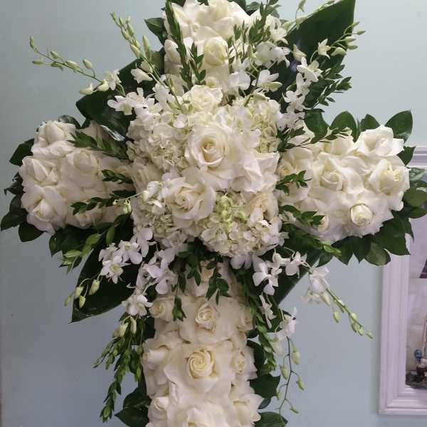 Large white floral cross arrangement with roses and orchids
