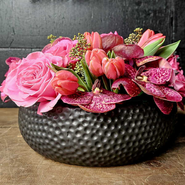 Pink roses and tulips arranged in a black textured bowl