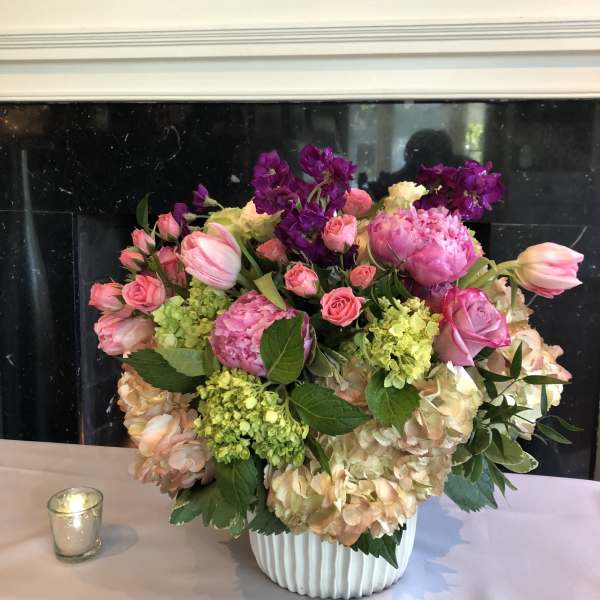 Pink and peach floral arrangement in a white vase