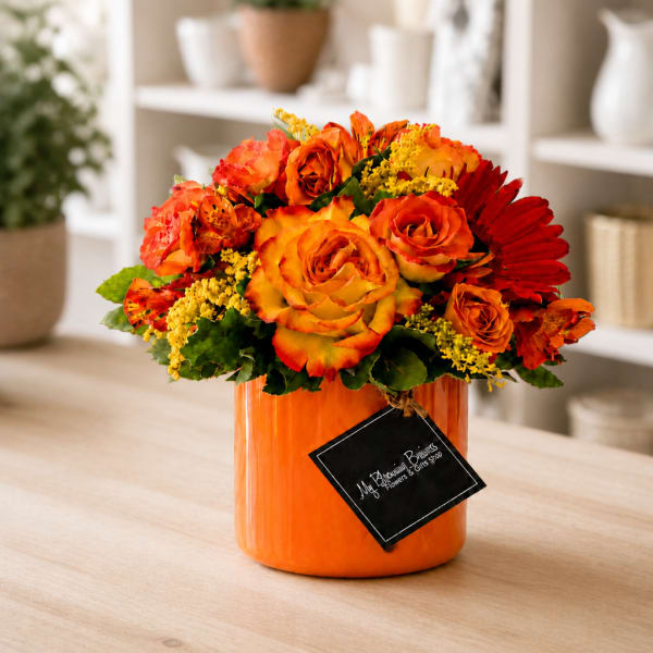 Orange and red rose arrangement in a bright orange vase