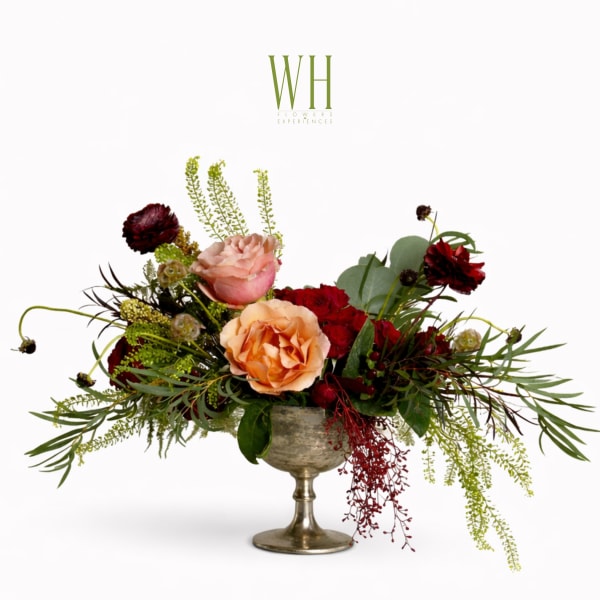 Mixed roses in a silver pedestal vase with trailing greenery