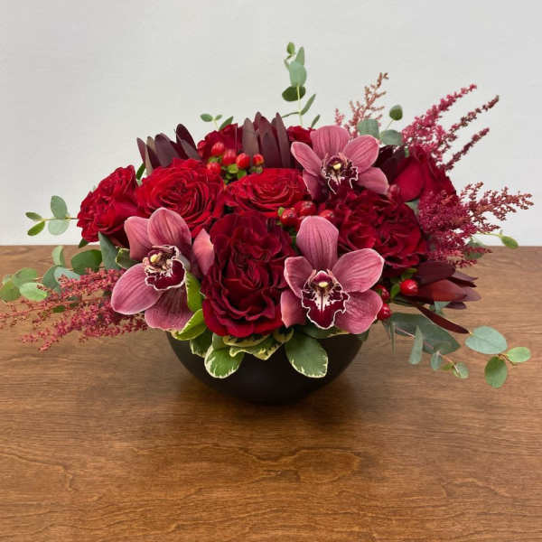 Red roses and pink orchids in a low black bowl
