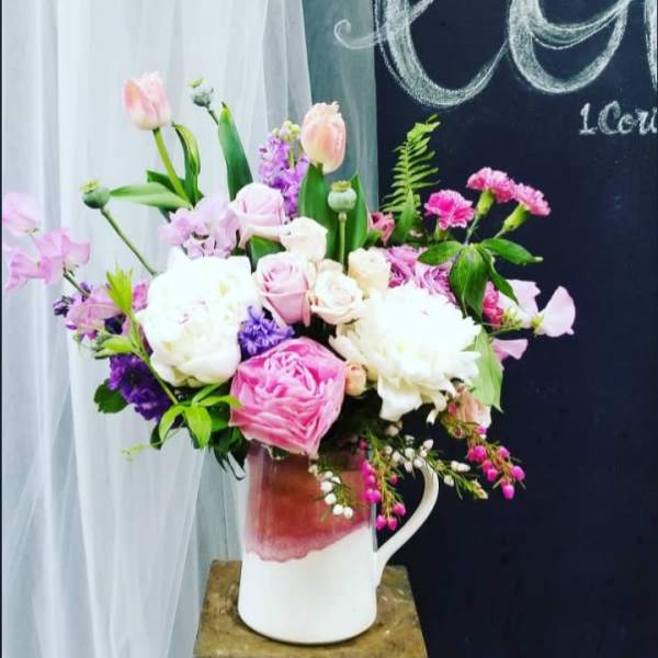 Pink and white mixed flower arrangement in a white pitcher vase