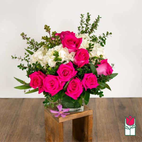 Pink roses and white hydrangeas in a glass vase with greenery