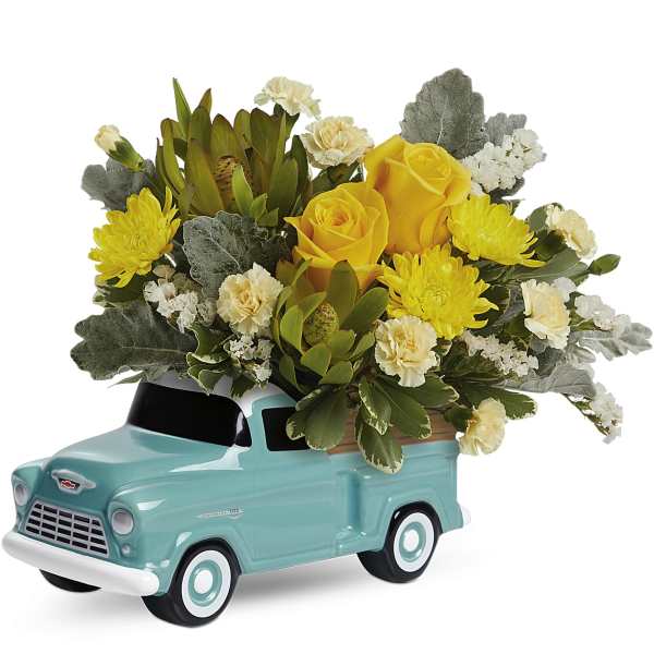 Yellow roses and chrysanthemums arranged in a turquoise truck planter