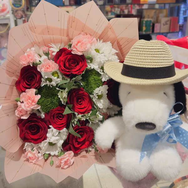 Bouquet of red roses and pink carnations with a plush dog wearing a hat