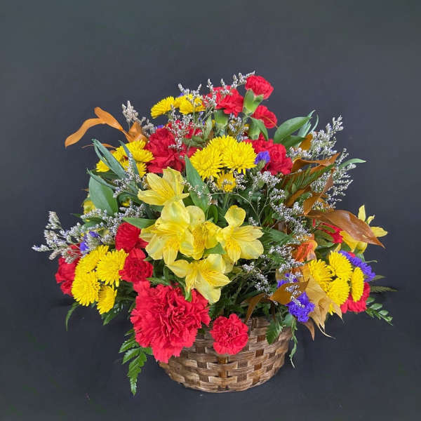 Mixed bouquet in a woven basket with red, yellow, and purple flowers