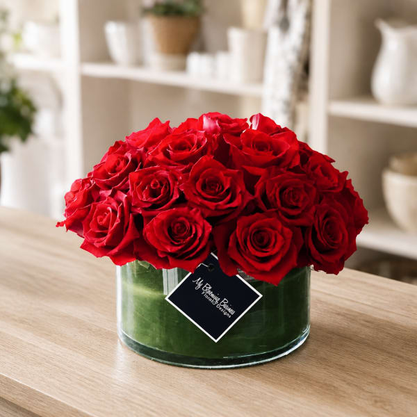 Red roses arranged in a clear glass vase on a table