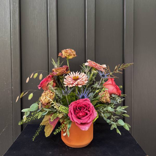 Mixed bouquet of pink and peach flowers in an orange vase