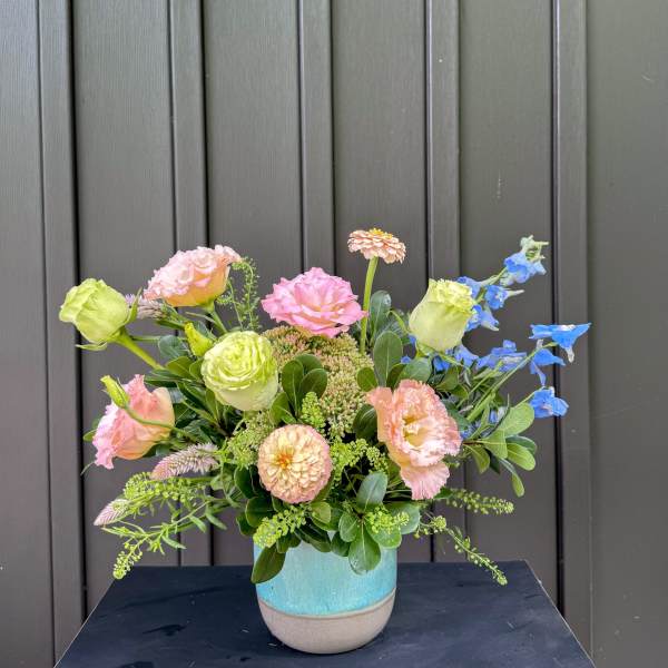 Pastel mixed flower arrangement in a blue ceramic vase