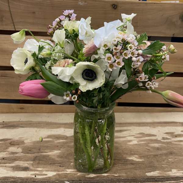 Mixed white and pink flowers arranged in a glass jar vase
