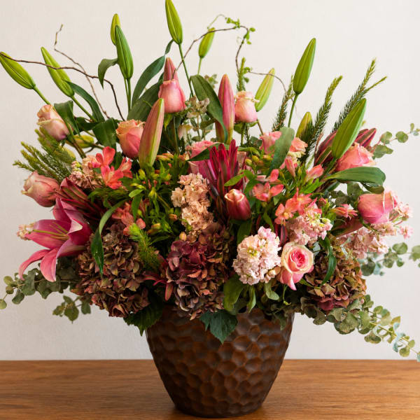 Pink lilies and roses arranged in a brown textured vase