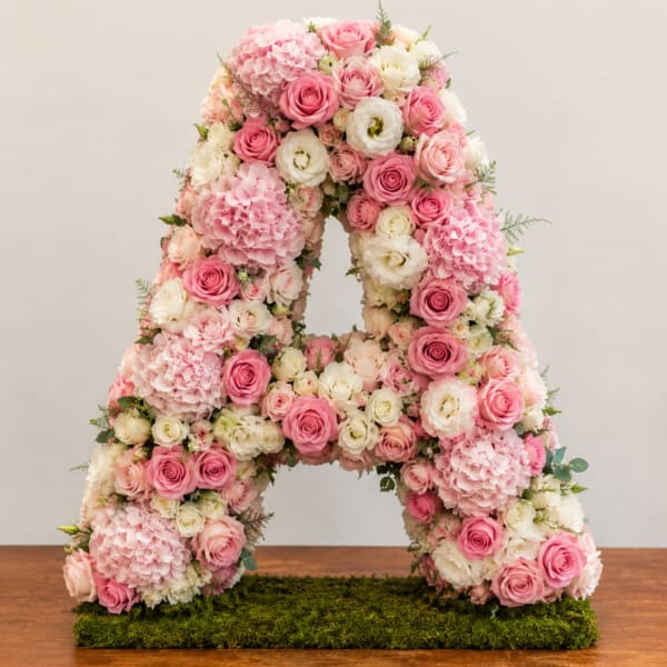 Pink and white floral letter A arrangement on a moss base