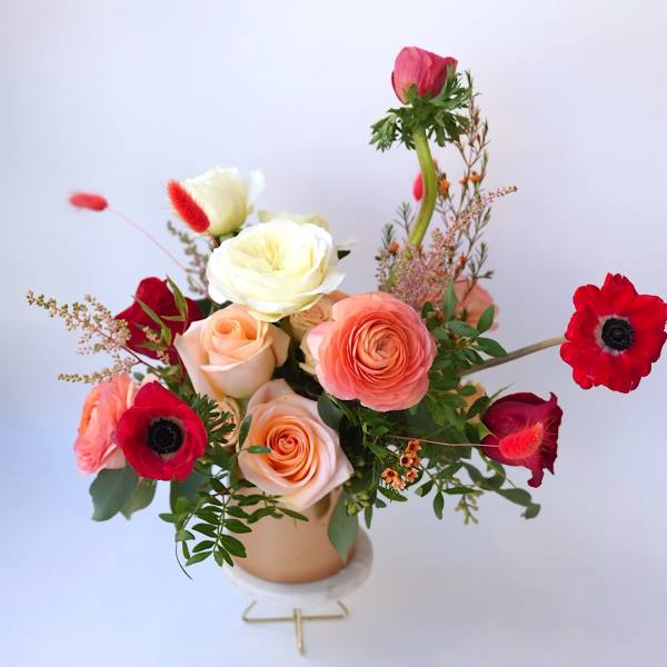 Mixed bouquet of roses and red anemones in a small vase