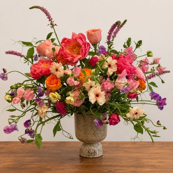 Colorful mixed flower arrangement in a speckled ceramic vase