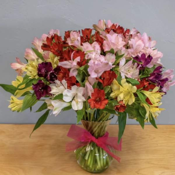 Mixed bouquet of colorful alstroemeria in a glass vase with a pink ribbon